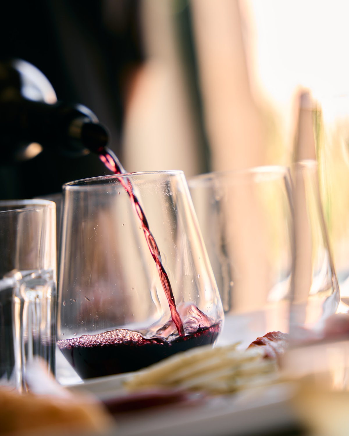 Vinho tinto a ser vertido para um copo sobre a mesa da prova