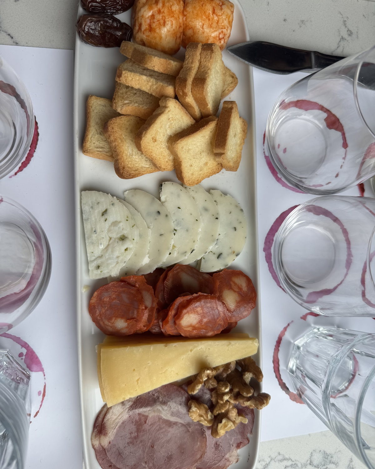 T&aacute;bua de queijos, enchidos e petiscos servida com copos de vinho